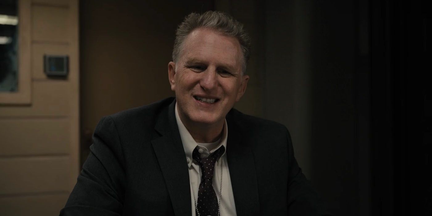 Michael Rappaport wearing a suit and tie, smiling ad detective Kreps in Only Murders in the Building.