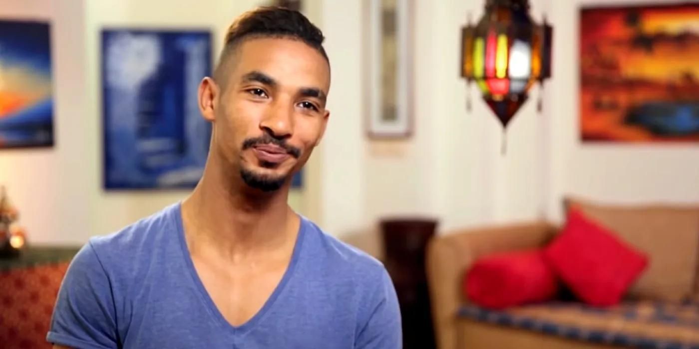 Azan Tefou from 90 Day Fiancé in a blue v-neck t-shirt smiling