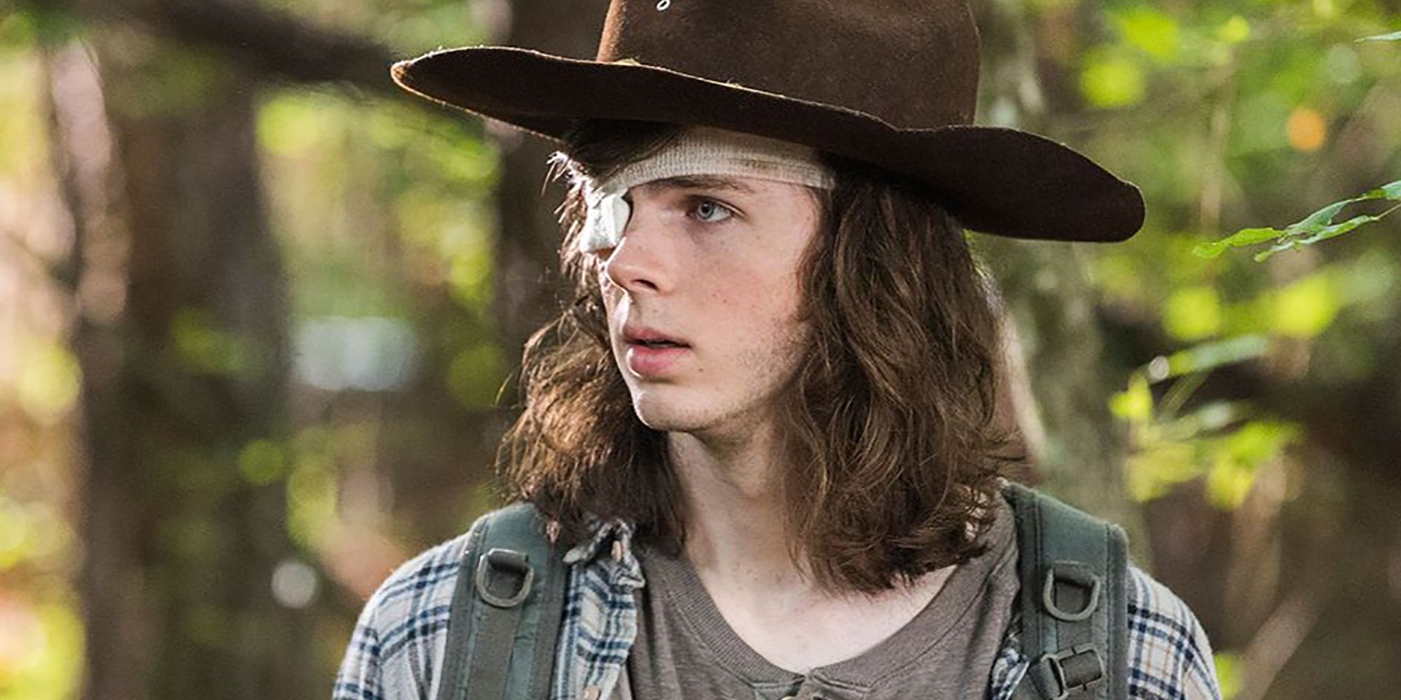 Carl looking to his right in the woods in The Walking Dead