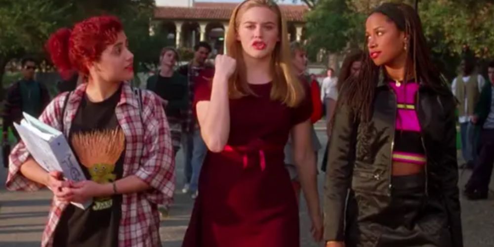 Cher walks between Tai and Dionne in a red dress at school in Clueless