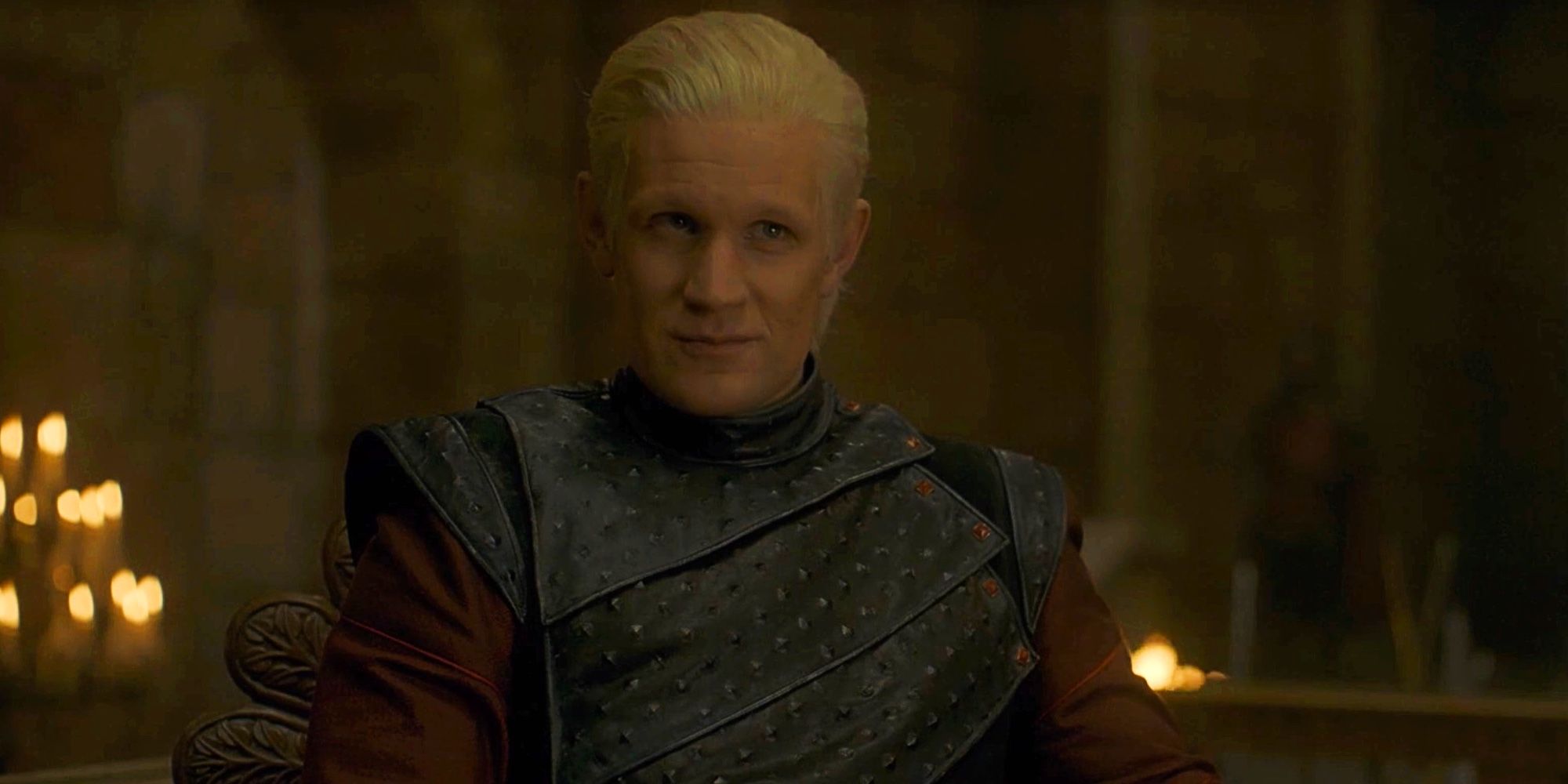 Daemon Targaryen sentado e sorrindo baixinho em House Of The Dragon.
