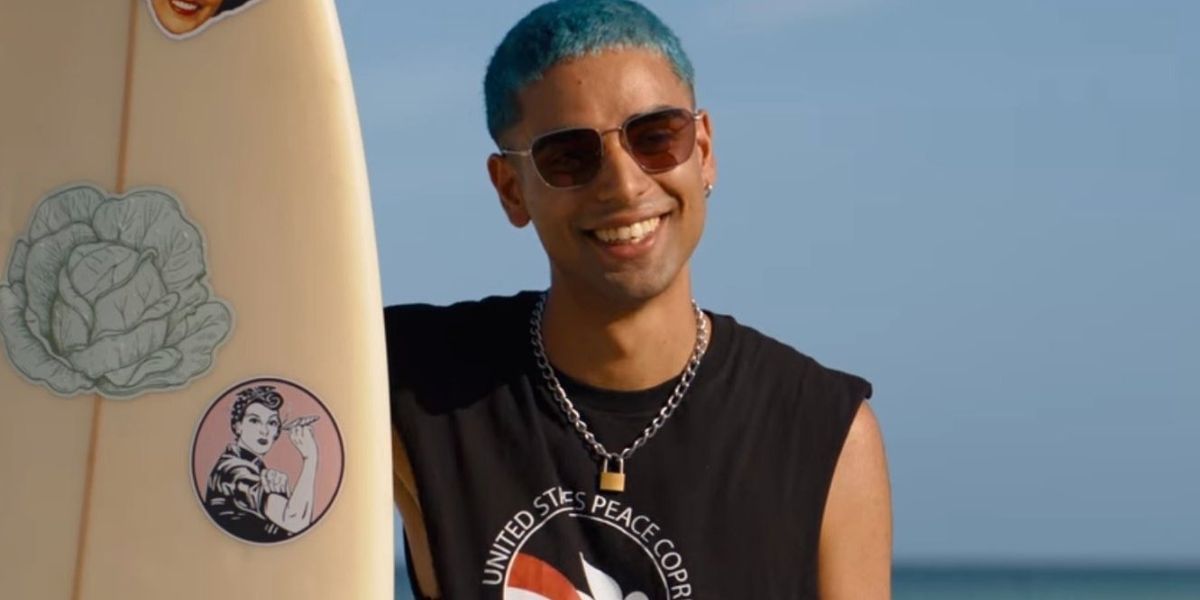 Russ holding a surfboard in Do Revenge and smiling