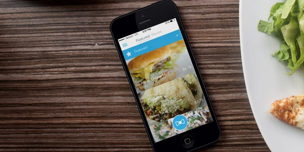 O aplicativo de comida Favor está aberto em um telefone ao lado de um prato de comida