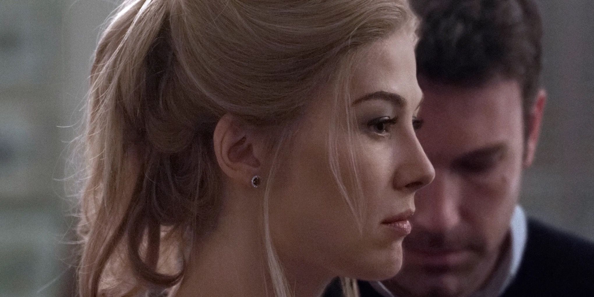 Rosamund Pike as Amy Dunne looking sad as Ben Affleck as Nick Dunne hangs his head in Gone Girl (2014)