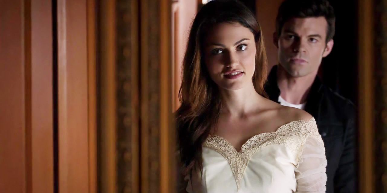 Hayley em um vestido de noiva com Elijah atrás dela.
