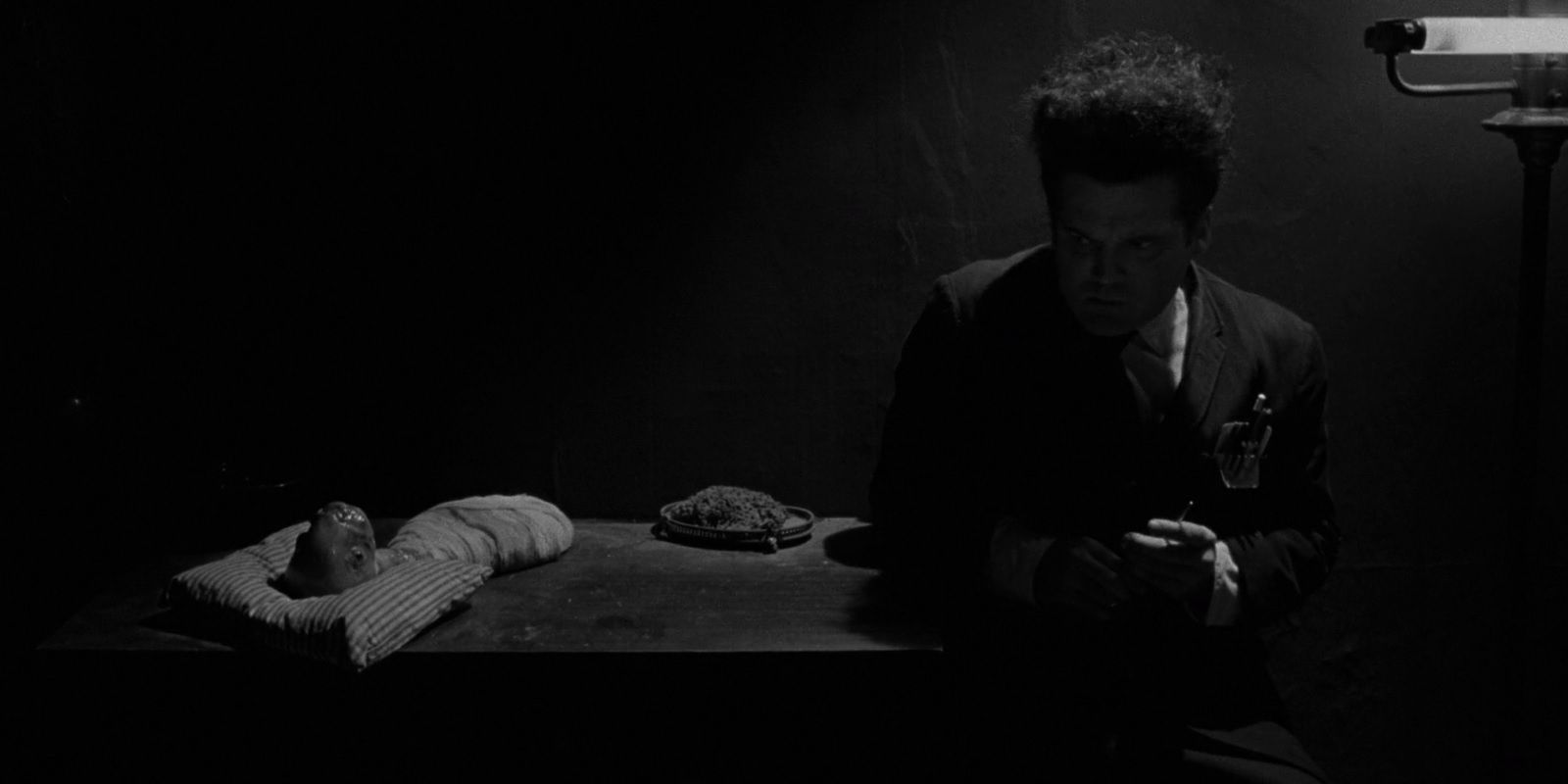 Henry sits next to his baby in Eraserhead