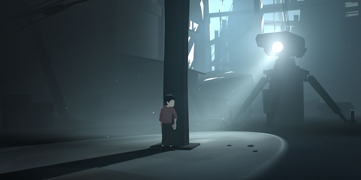 The boy from Inside hiding behind a pillar as a robot looks for him with a searchlight