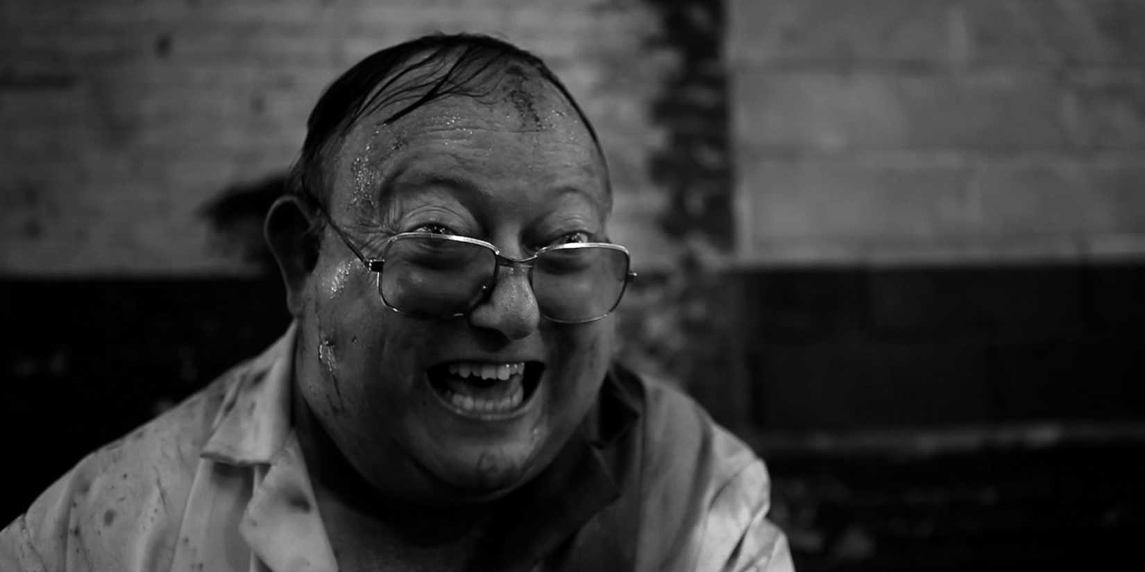 Laurence R. Harvey as Martin Lomax smiles maniacally in The Human Centipede 2