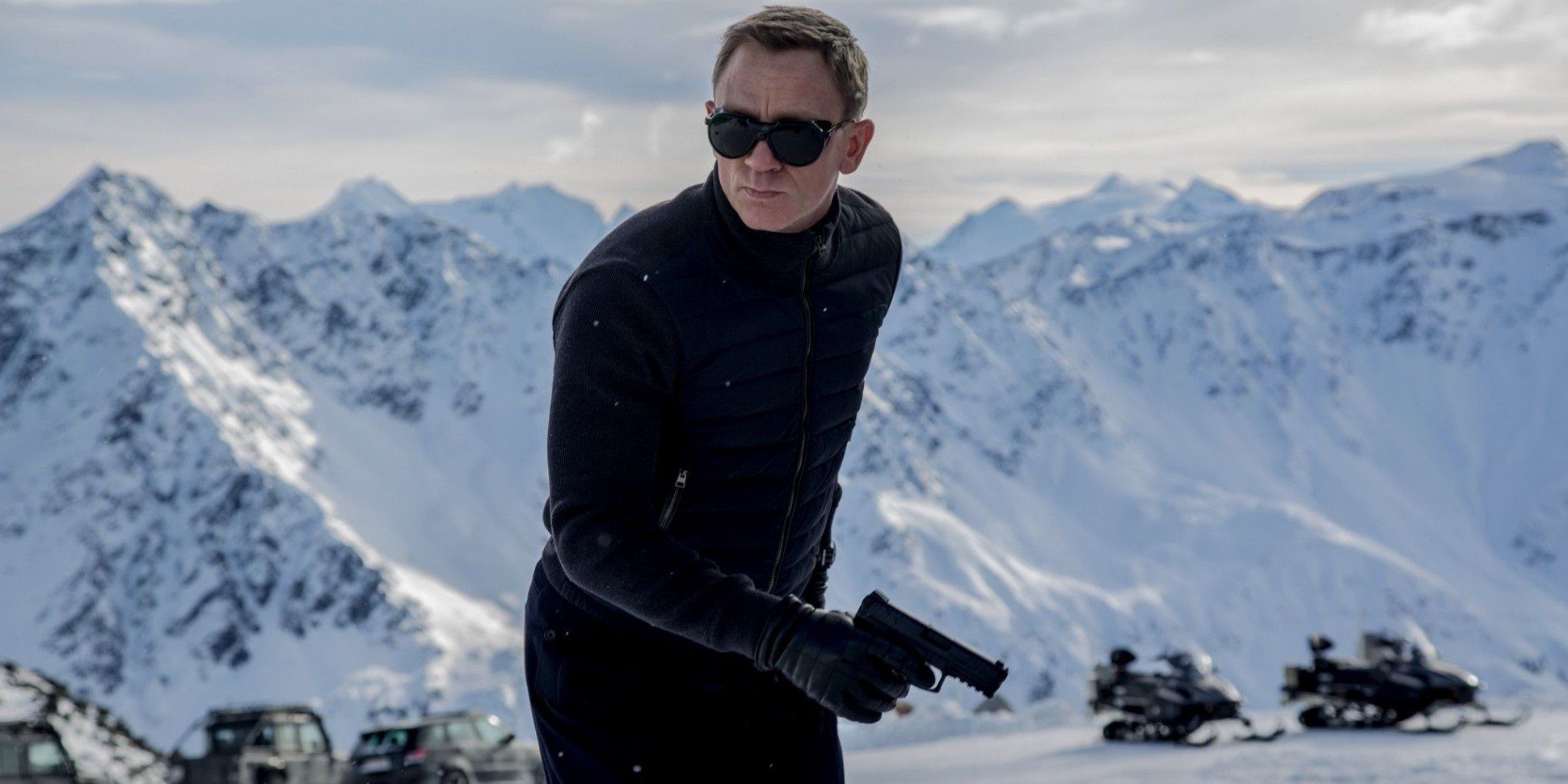 James Bond standing in the snow with a gun in Spectre