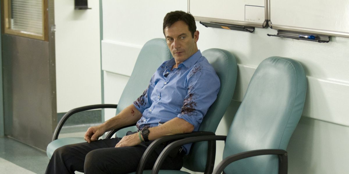Jason Isaacs sitting in a chair with blood on his shirt in Awake