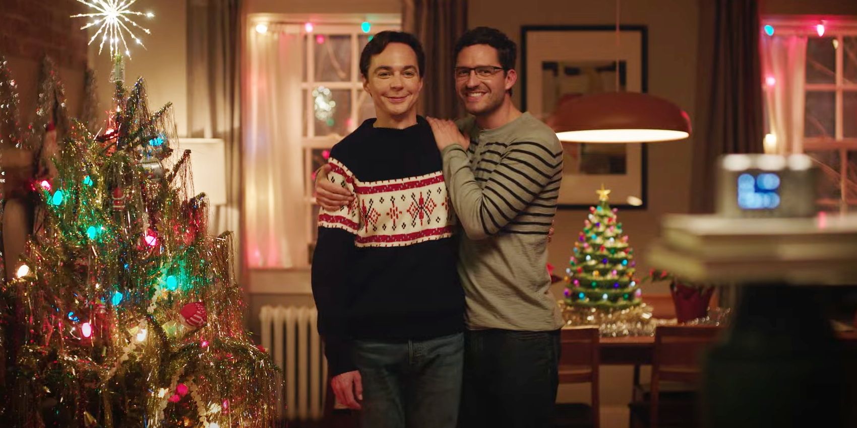 Jim Parsons as Michael Ausiello and Ben Aldridge as Kit Cowan standing by Christmas tree in Spoiler Alert movie