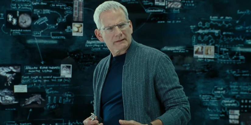Campbell Scott as Jurᴀssic World Dominion's Lewis Dodgson standing in front of a board with notes 