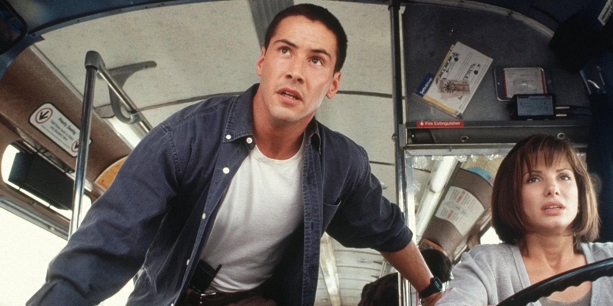 Officer Jack Traven (Keanu Reeves) holding on tight on the bus as Annie Porter (Sandra Bullock) drives in Speed