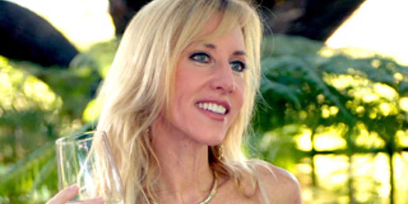 Kim Bryant smiling with a glass of wine on RHOC