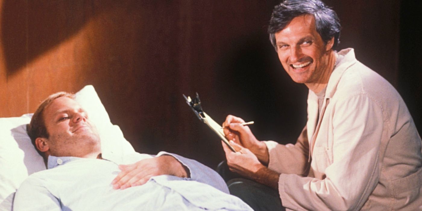 Alan Alda as Captain Hawkeye Pierce smiles while checking a patient on MASH