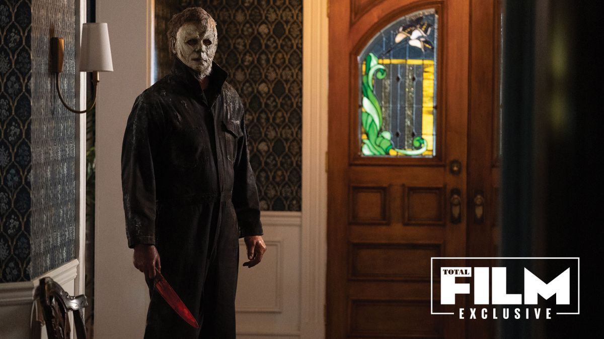 Michael Myers in Halloween Ends with his mask on holding a bloody knife at his side