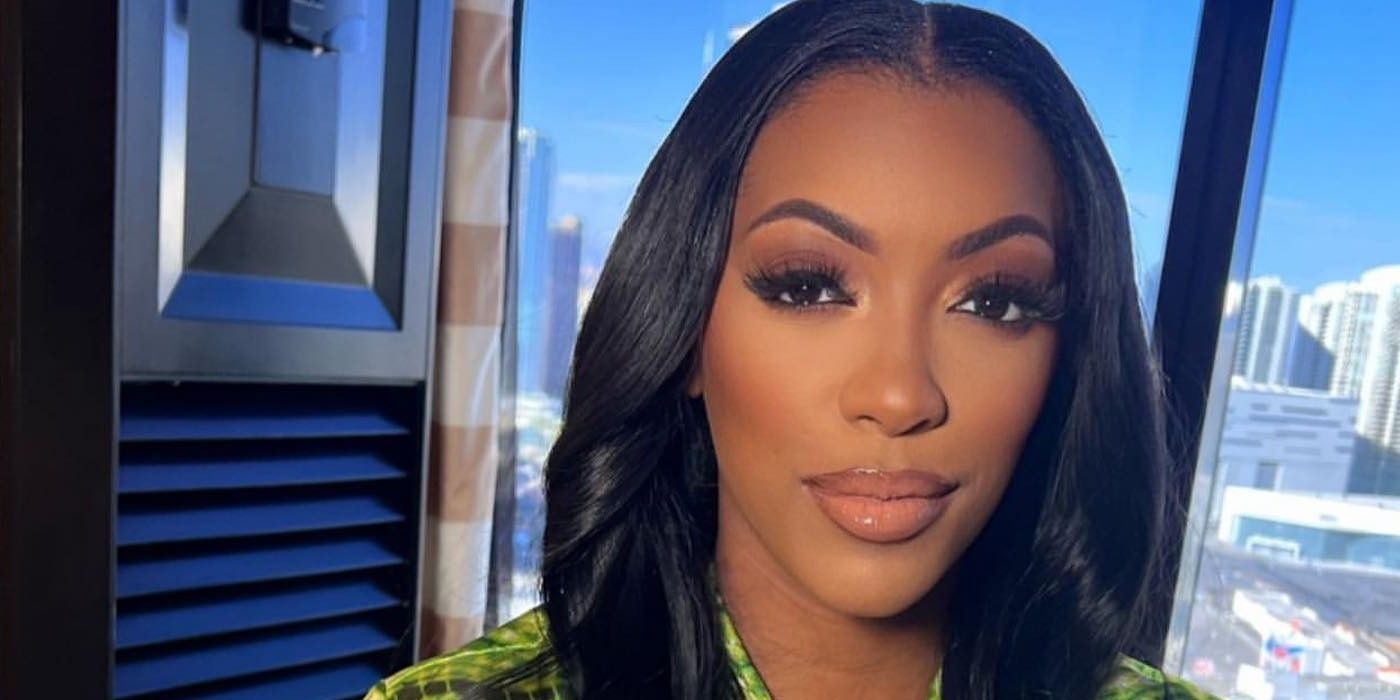 RHOA Porsha Williams green shirt posing in hotel closeup with skyline in the background