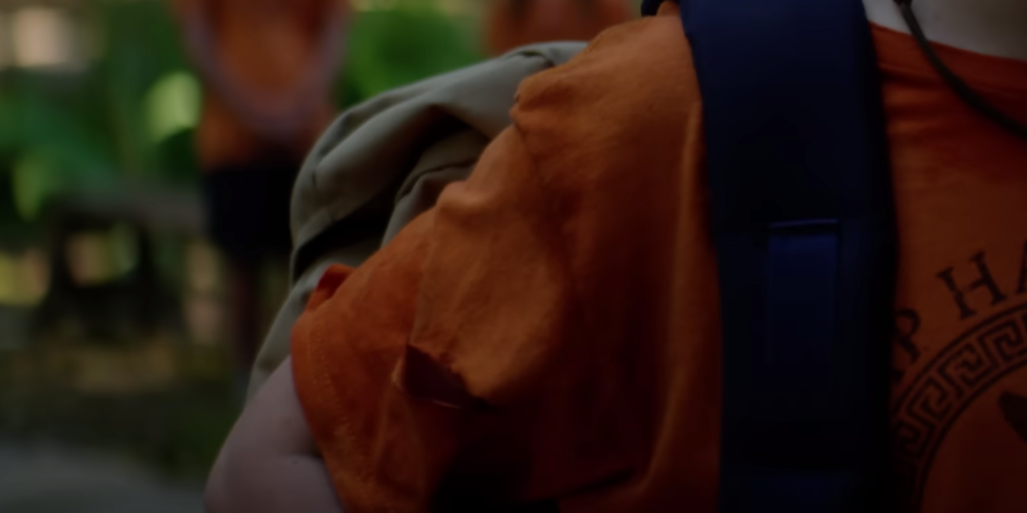 A close-up of Percy's orange Camp Half-Blood shirt with a tear in the right sleeve from Percy Jackson and the Olympians