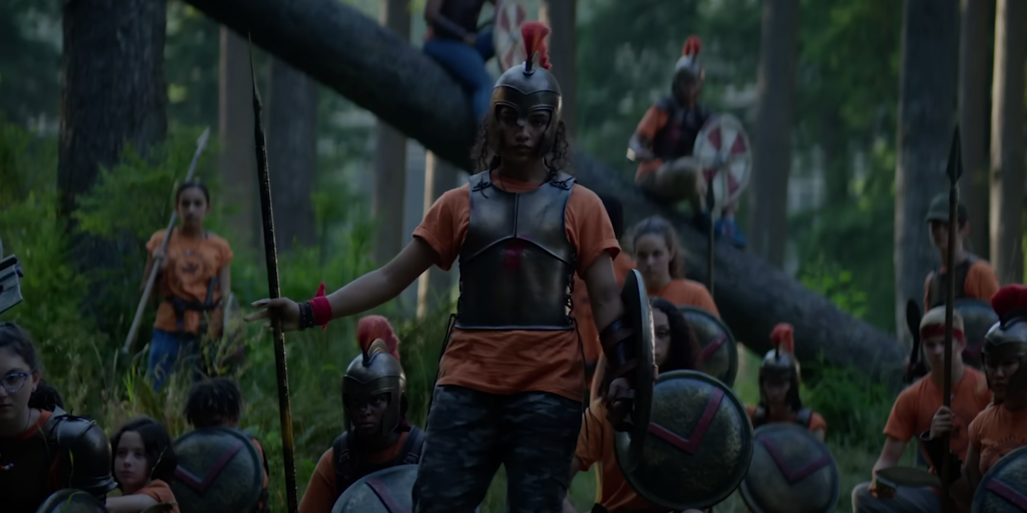 Clarisse with a shield and spear surrounded by similarly-dressed campers in Percy Jackson and the Olympians