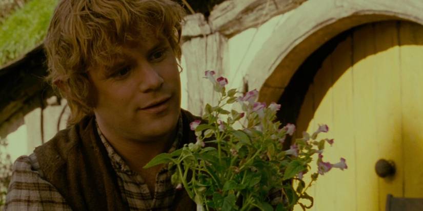 Sean Astin as Samwise Gamgee holding flowers and smiling.