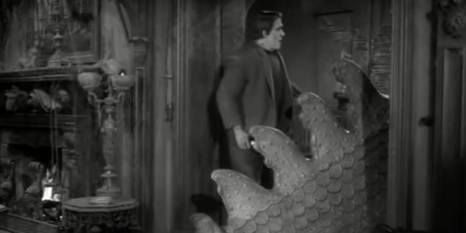 Fred Gwynne como Herman Munster olhando para a cauda de um monstro gigante em The Munsters
