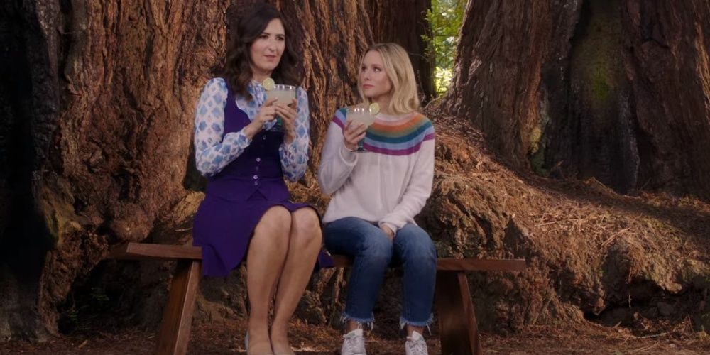 Two women have a drink by a tree in The Good Place