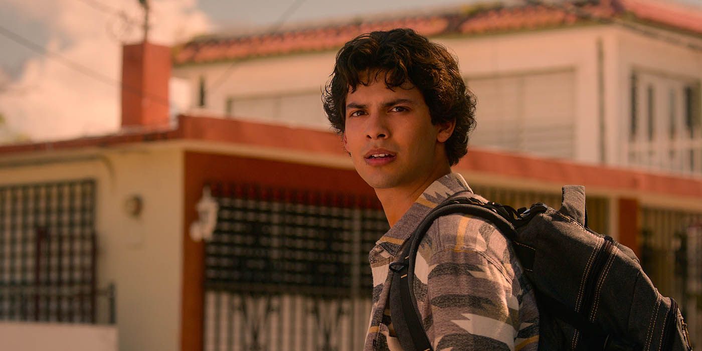Miguel parado no México com uma mochila, olhando algo em uma cena de Cobra Kai.
