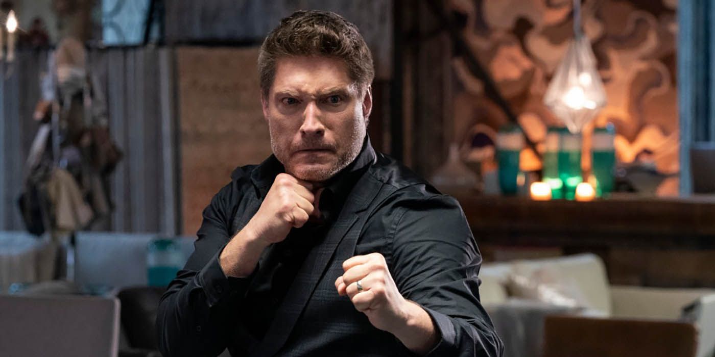 Mike Barnes, fists in the air in his furniture store, face ready to fight in a scene from Cobra Kai