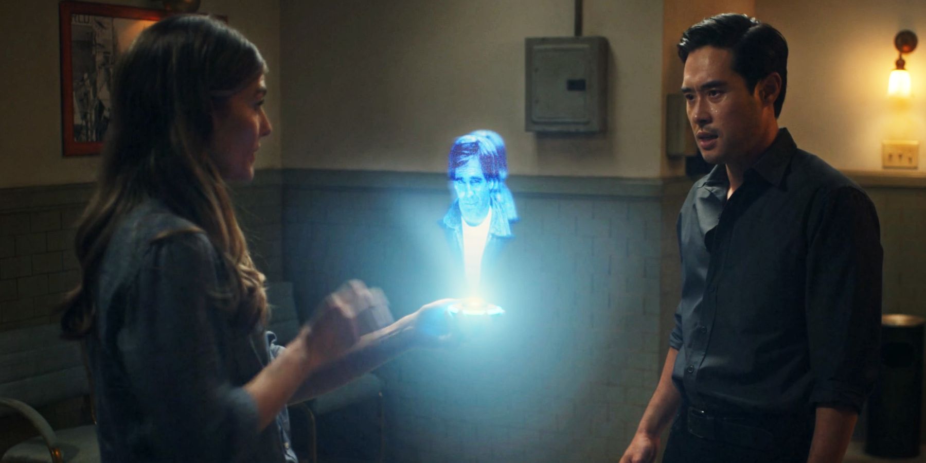 Caitlin Bassett e Raymond Lee olham para uma imagem de Scott Bakula como Sam Beckett em Quantum Leap