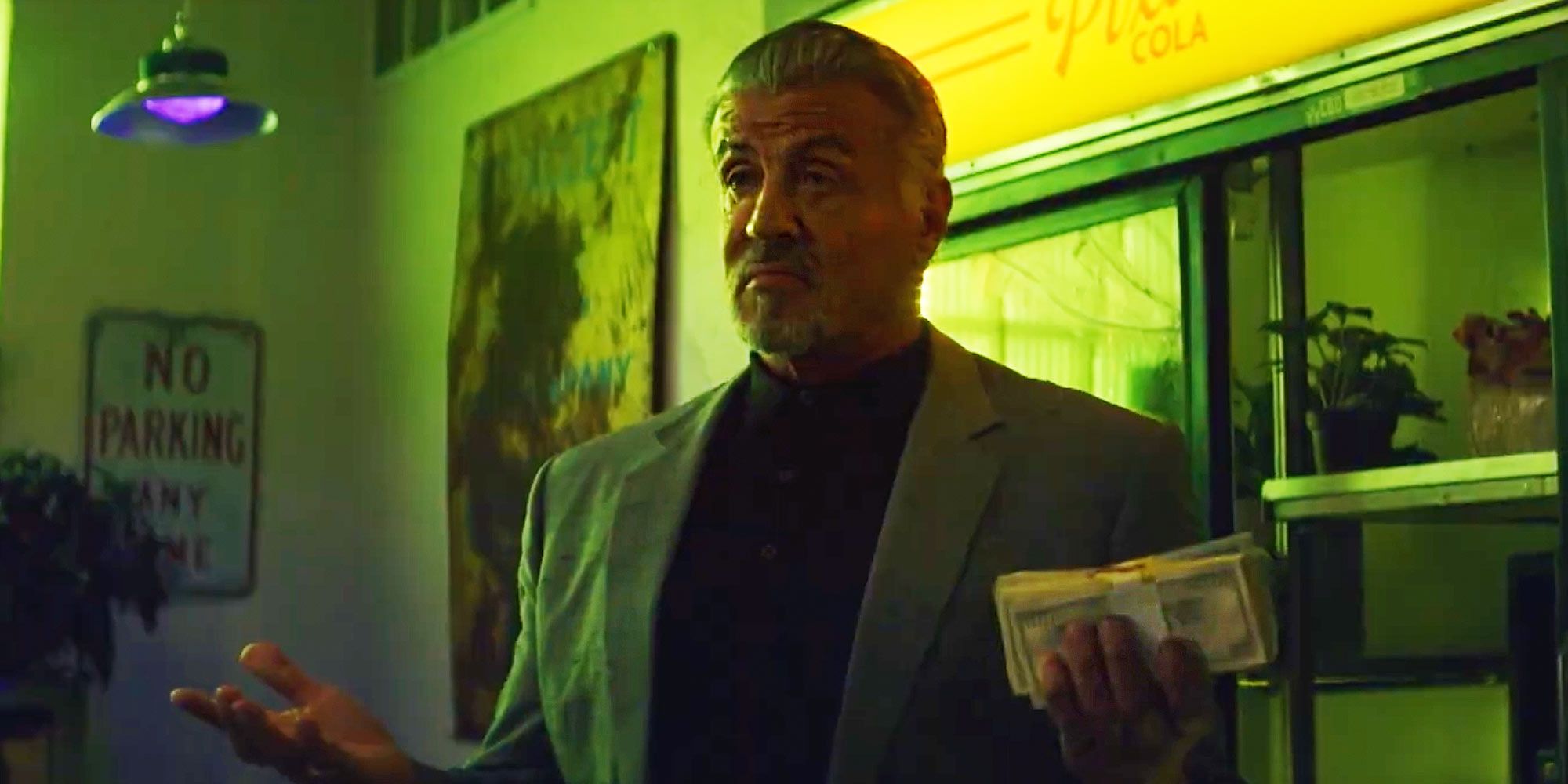 Sylvester Stallone in Tulsa King holding a stack of cash with a smug look on his face.