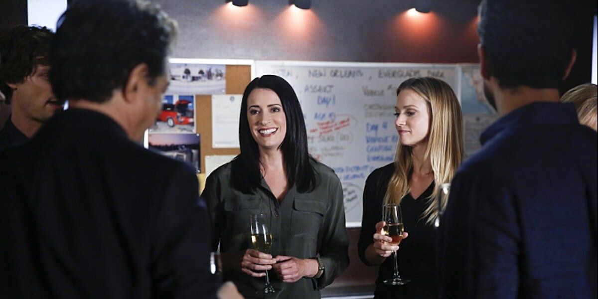 Emily smiles while holding a champange glass with the rest of the BAU.