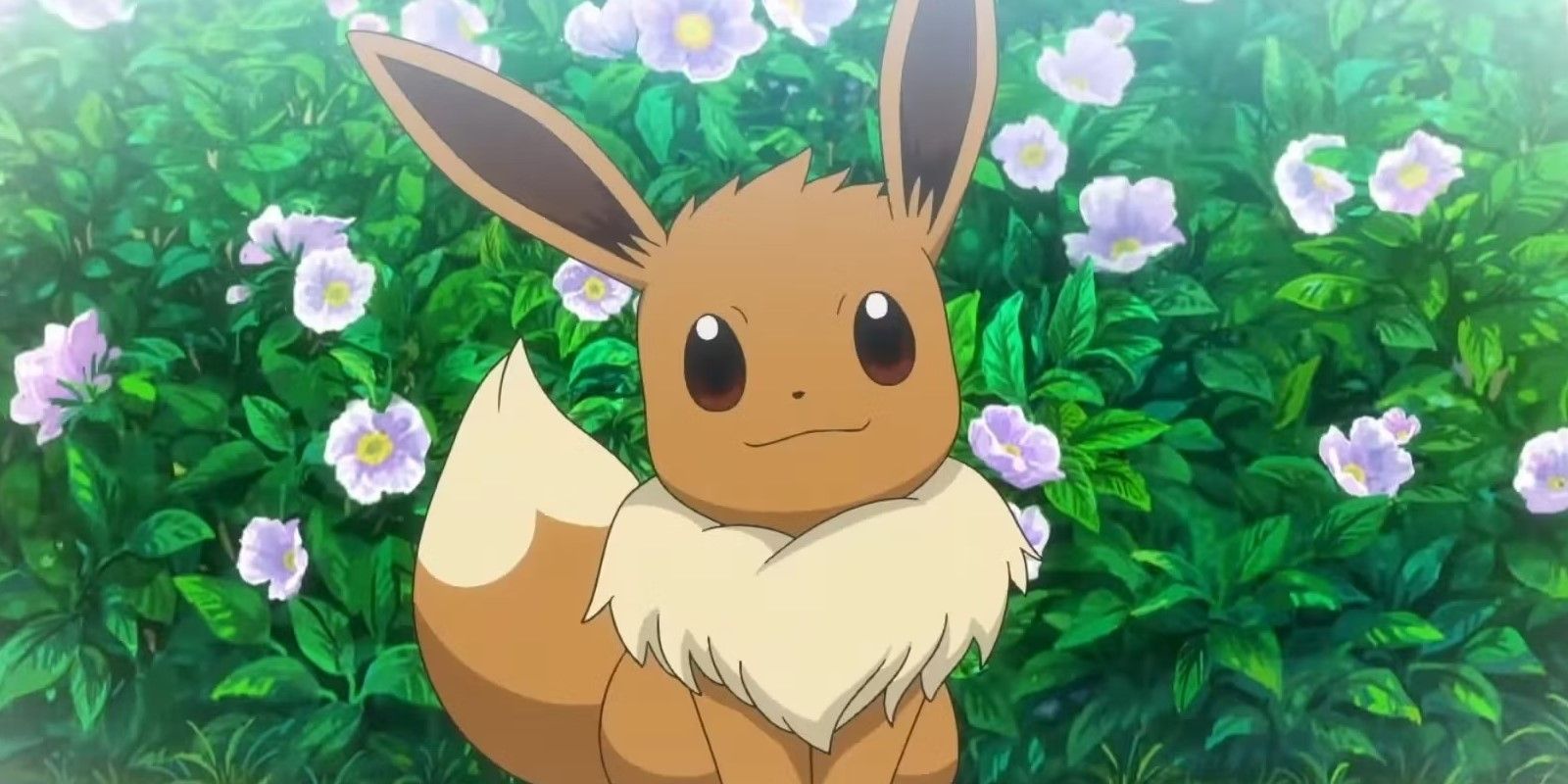 Eevee dari Pokémon tersenyum di depan semak bunga.