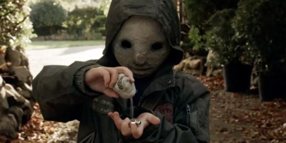 A masked kid pours something in his hand in Creeped Out