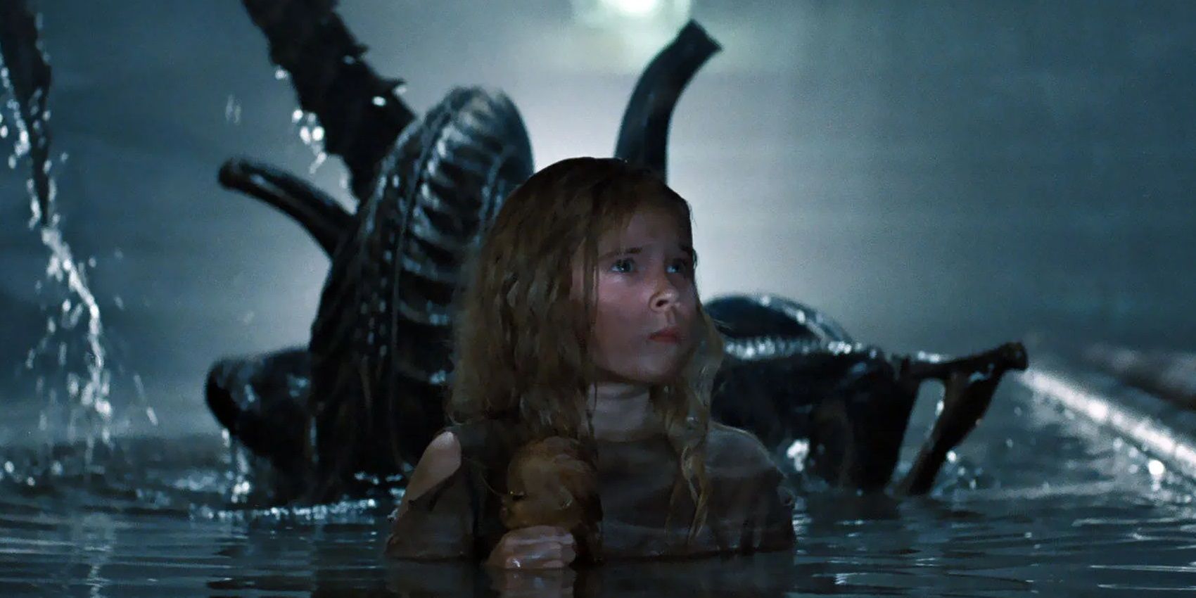 A xenomorph rises up behind Newt in Aliens
