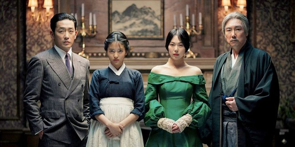 Four people wearing fancy clothes pose for a photo in The Handmaiden