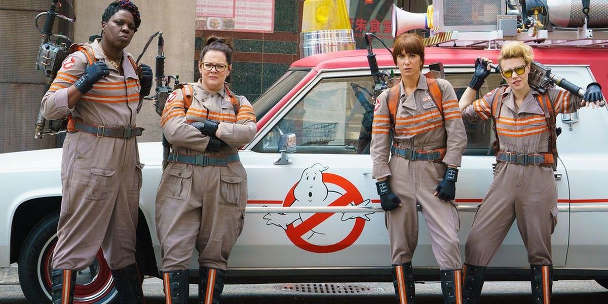 The female Ghostbusters standing in front of the Ecto-1
