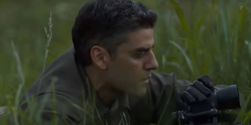 Oscar Isaac sitting in the grass in Operation Finale