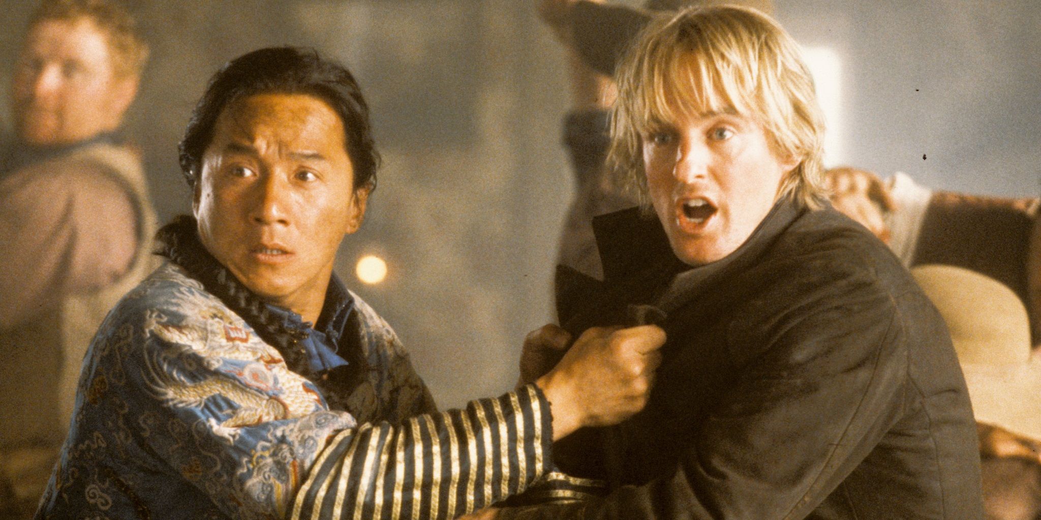 Jackie Chan and Owen Wilson grabbing each other and looking at something in a saloon in Shanghai Noon
