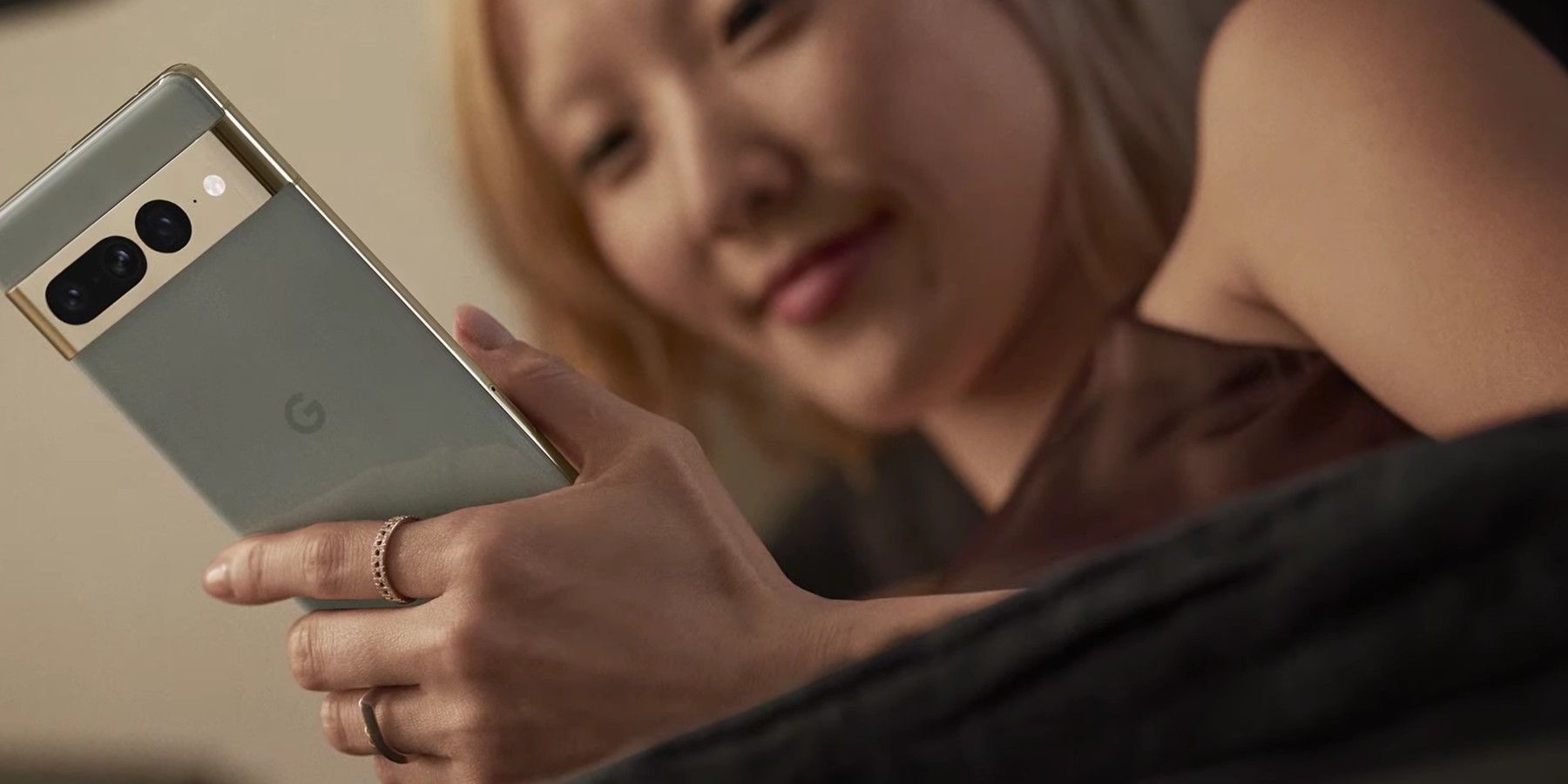 A blonde woman is pictured from below, holding a silver Pixel 7