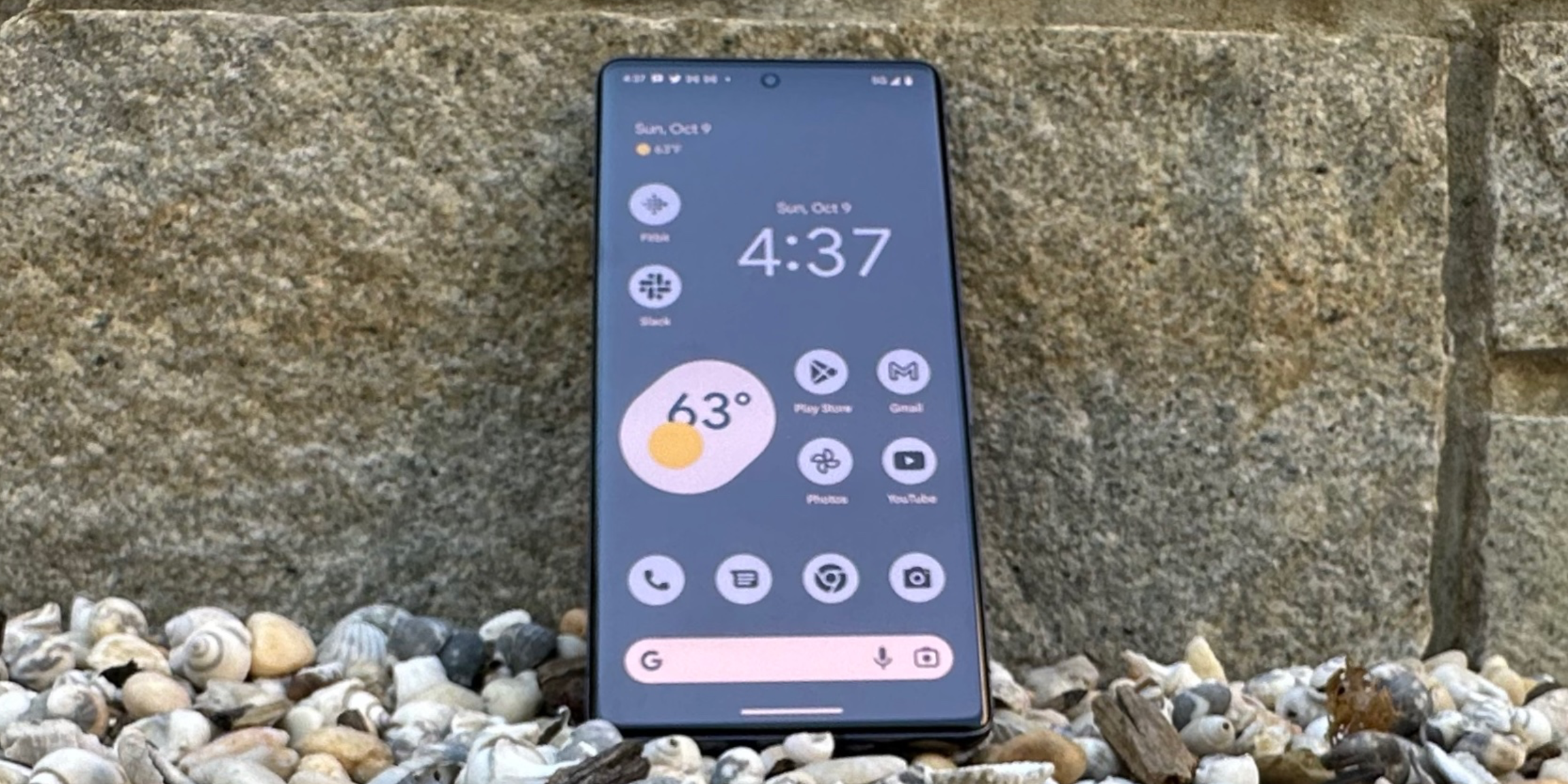 Pixel 7 Pro&rsquo;s Home Screen in front of brick and gravel background.
