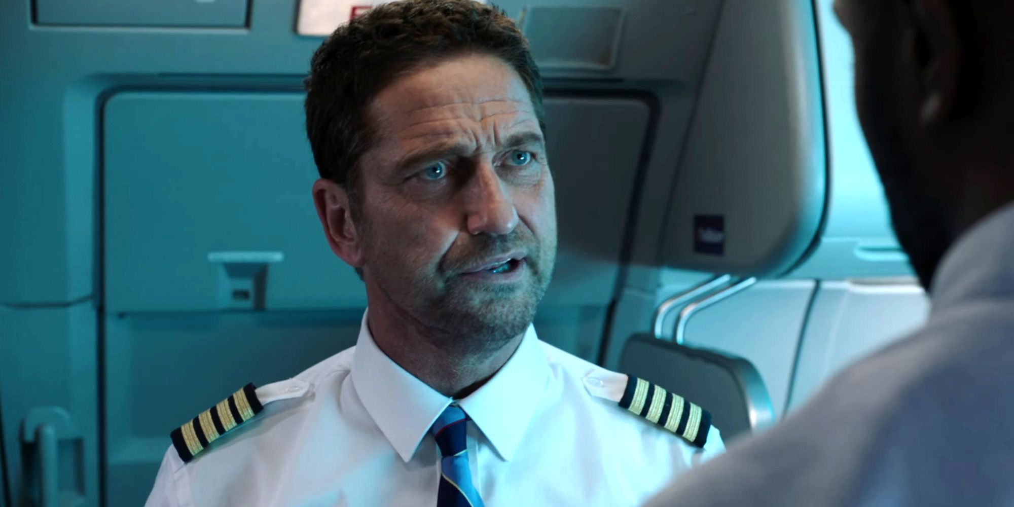 An image of Gerard Butler talking to the pilot in Plane