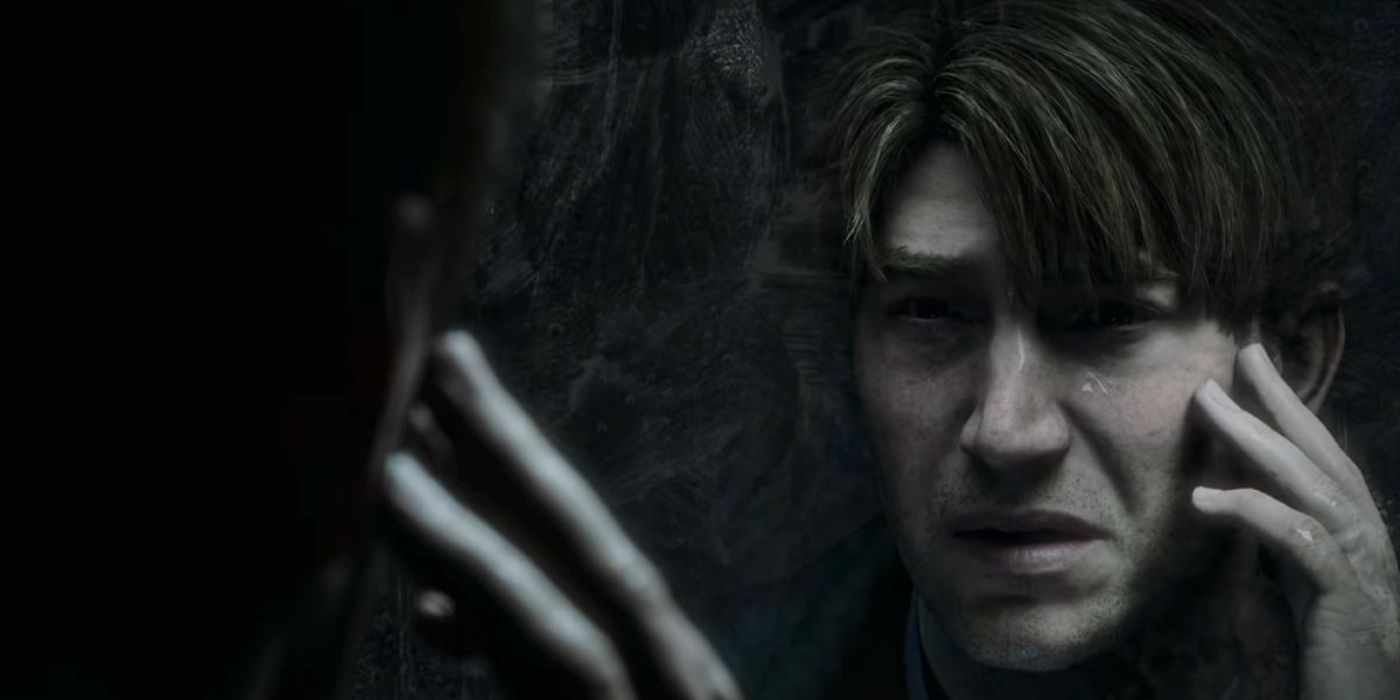 A screenshot of the trailer for the remake of Silent Hill 2, with James Sunderland staring into a miror and touching his cheek with his fingers.