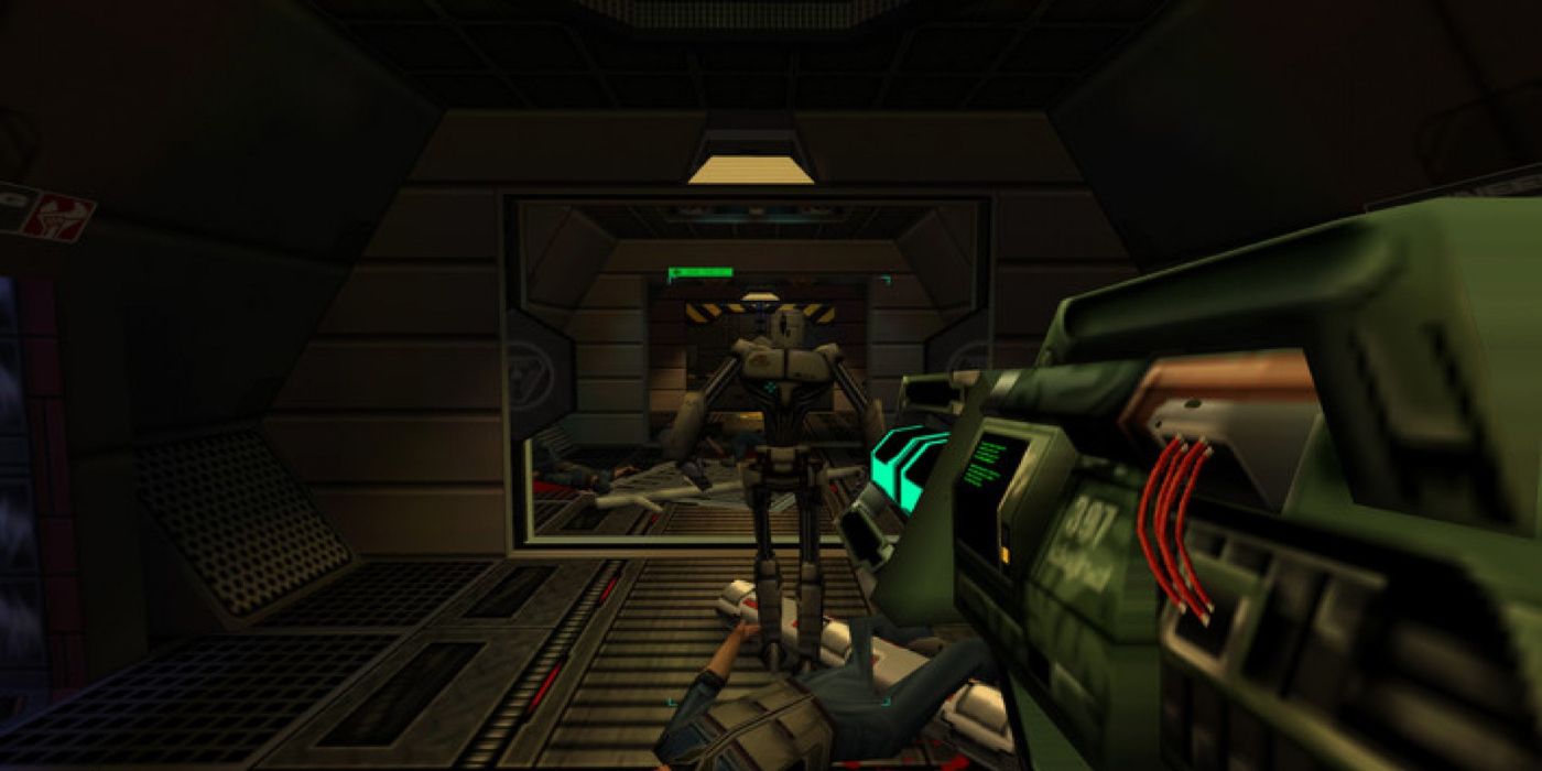 A robot walking down a dark hallway in System Shock 2 with the player aiming a futuristic weapon in its direction.
