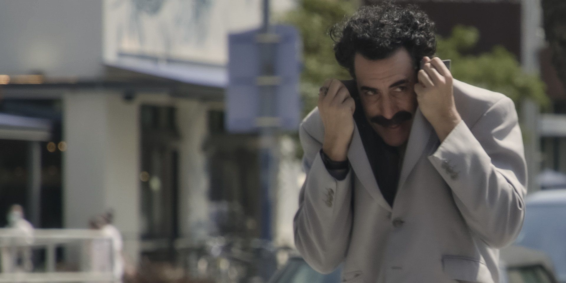 Sacha Baron Cohen hiding his face in Borat Subsequent Moviefilm