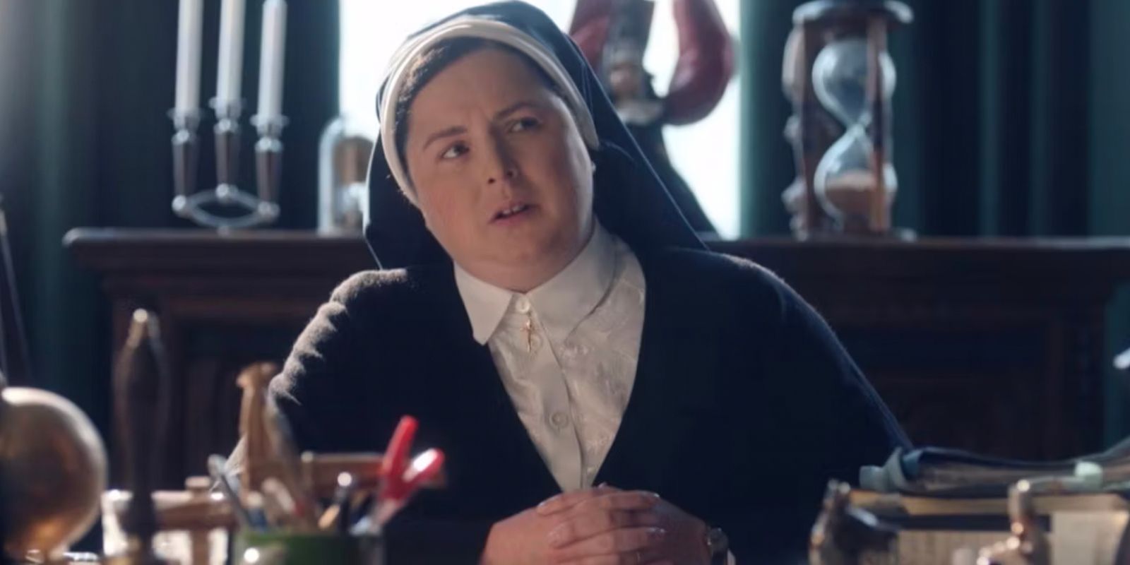 Sister Micheal leans away at her desk in Derry Girls
