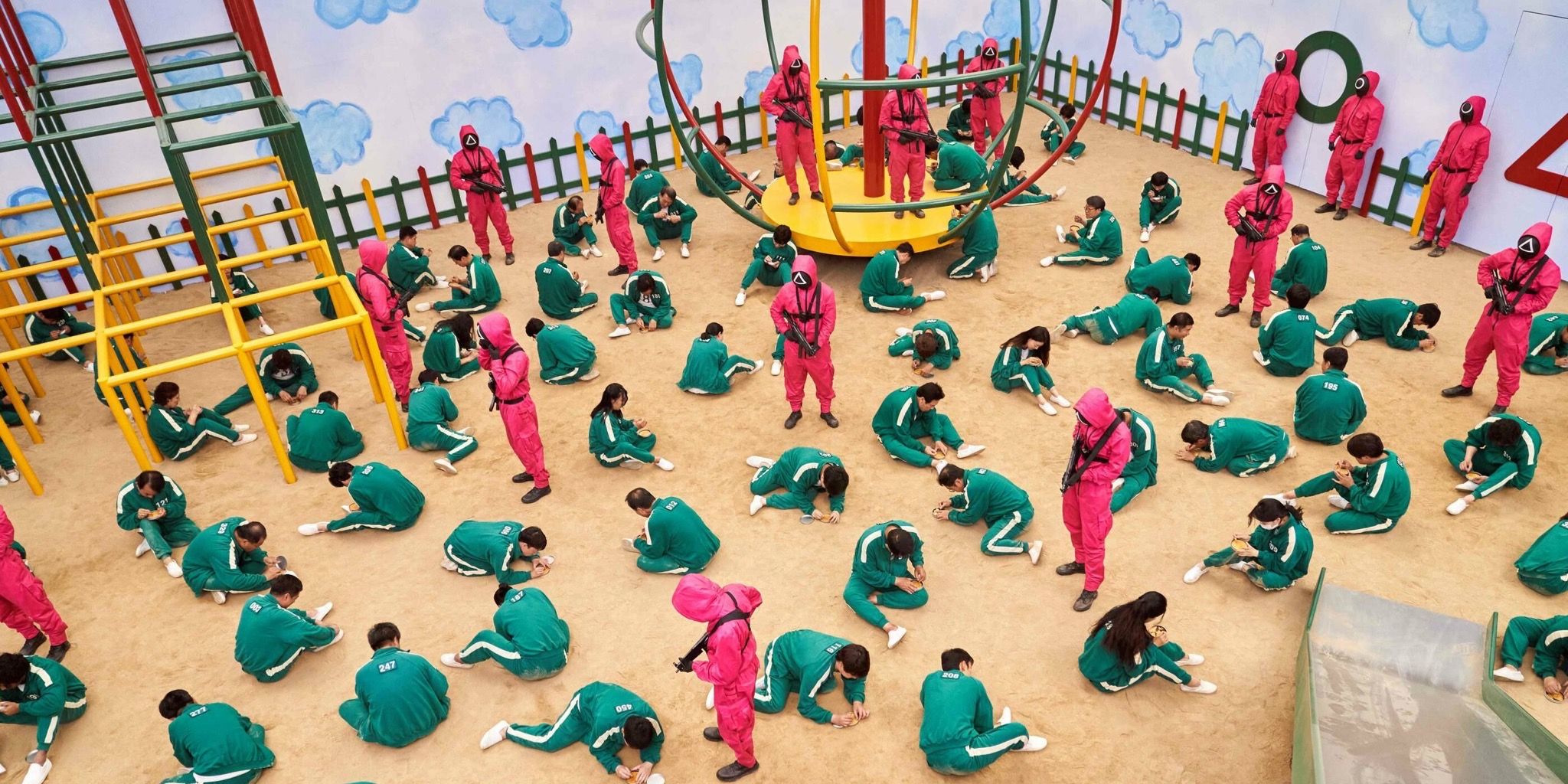 Everyone competing in Squid Game with players in green tracksuits and guards in pink ones