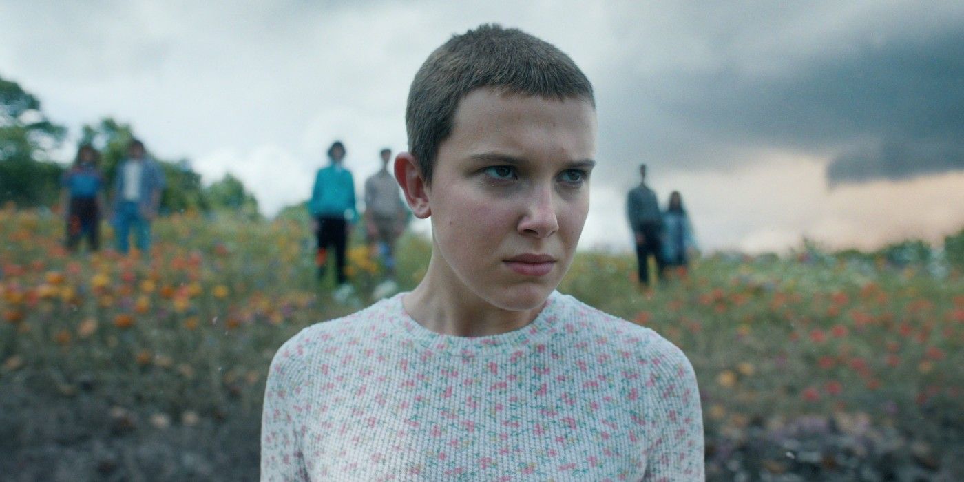 Eleven standing in a field with her friends behind her in Stranger Things.