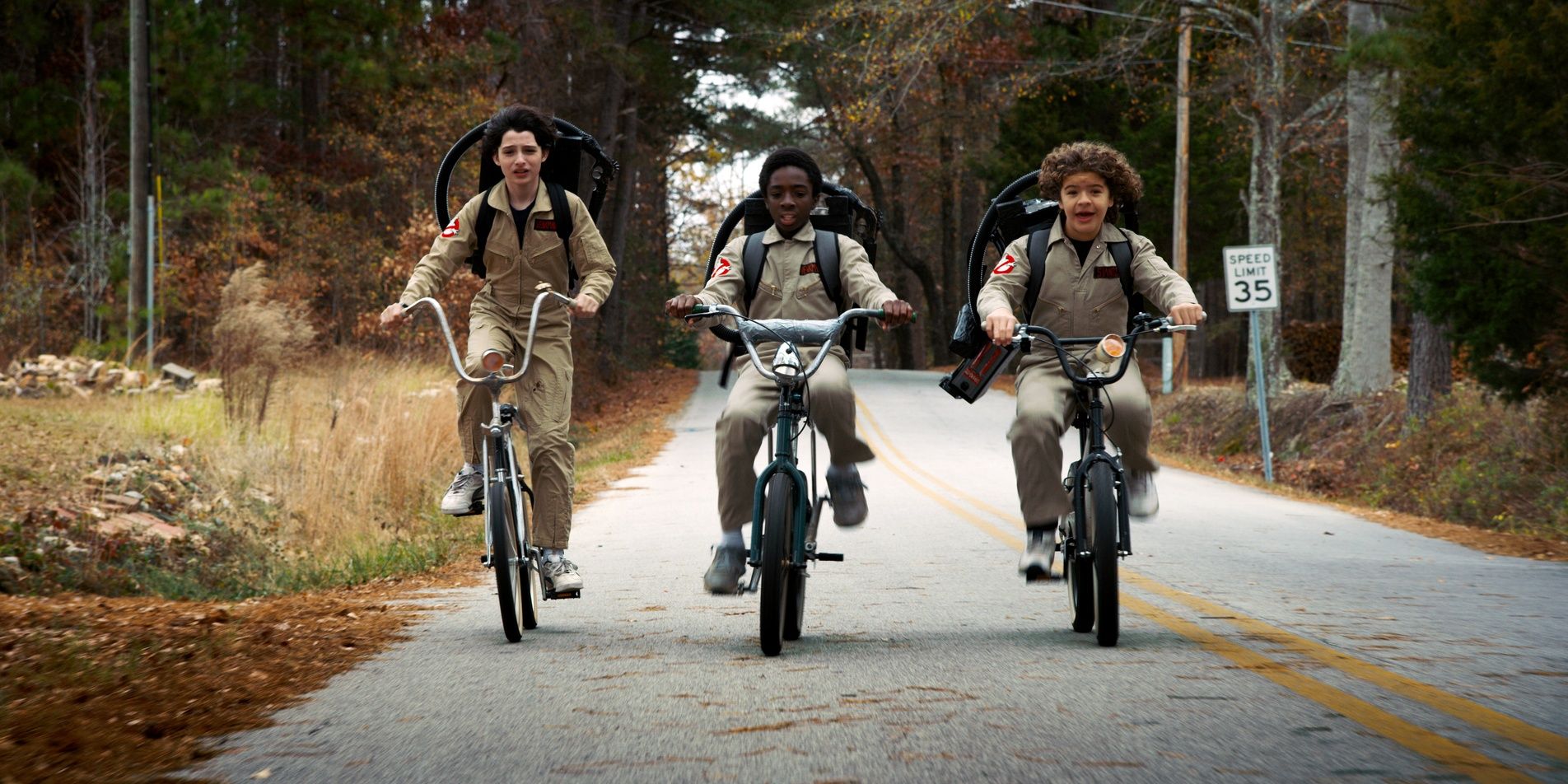 Three boys ride bikes on the street in Stranger Things 