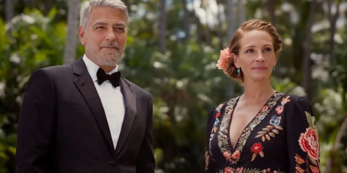 George Clooney in a black tux and Julia Roberts in a floral dress looking into the distance in Ticket To Paradise