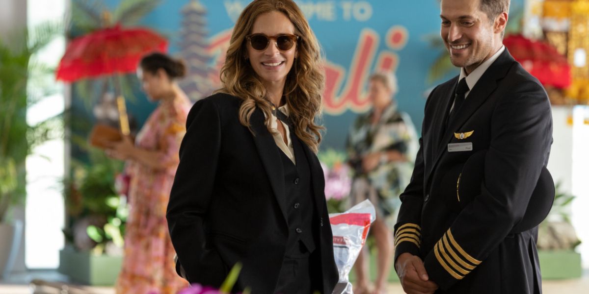Julia Roberts in sunglasses standing next to pilot at the airport in Ticket To Paradise
